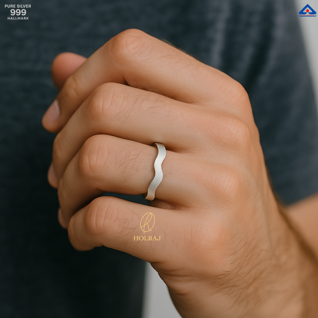 Male Hand wearing 999 silver ring with 'HOLRAJ' branding on a blurred background