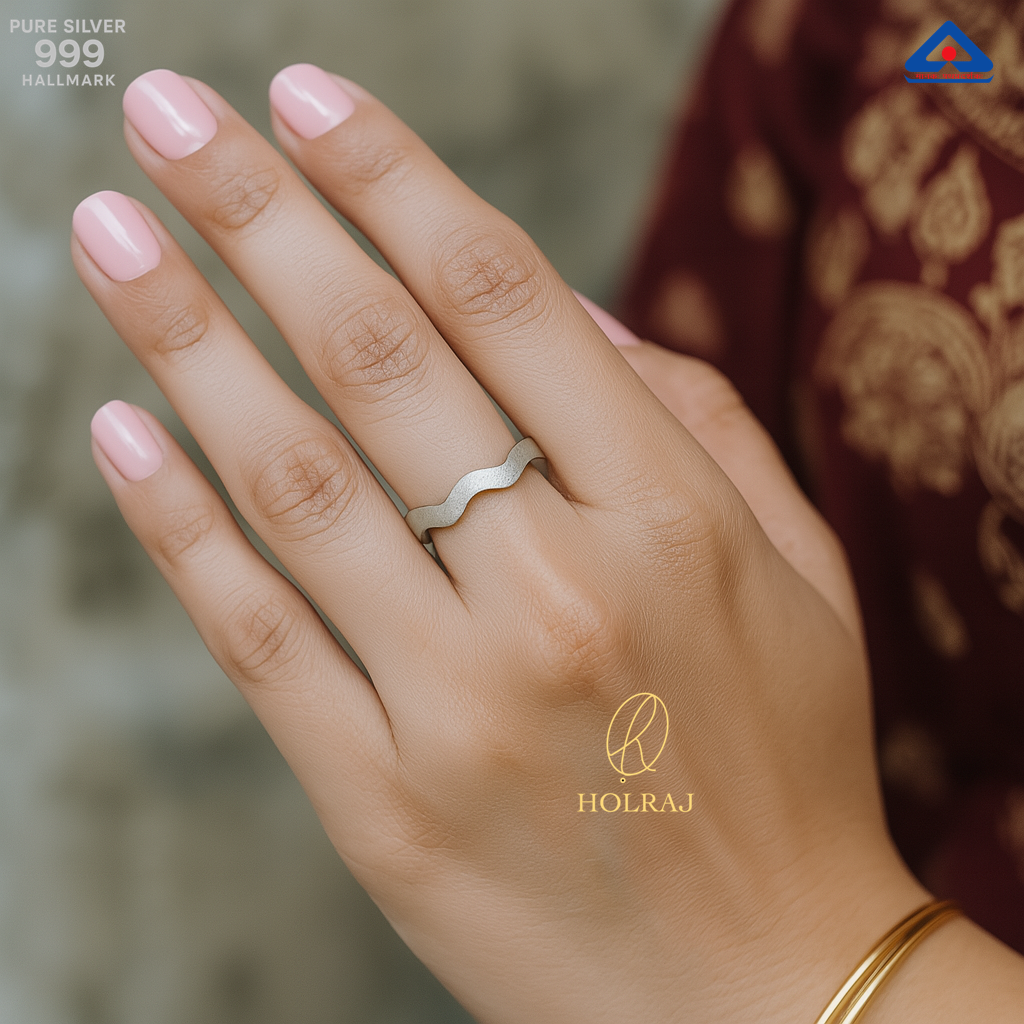 Female Hand wearing a 999 pure silver ring with 'HOLRAJ' branding, against a blurred background.