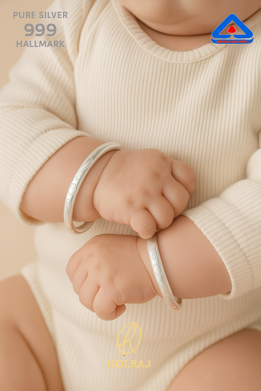 Child or a baby wearing two BIS Hallmark 999 pure silver bangles or kada or bracelets with holraj branding.