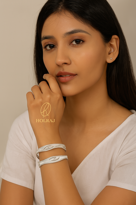 Woman wearing Pair of Pure 999 Silver bangles with minimalist S-curve engravings and beaded edges, photographed on a beige background with BIS Hallmark - by HOLRAJ.