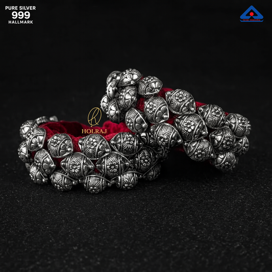 Close-up of Holraj’s Phool Ponchi bracelet handcrafted in 999 pure silver with floral dome patterns on red velvet, displayed on a black surface.