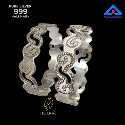 Pair of pure 999 silver bangles featuring a wavy edge and paisley engravings, displayed on a black background with hallmark and Holraj logo.
