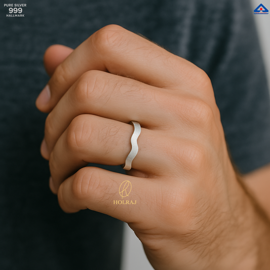 Male Hand wearing 999 silver ring with 'HOLRAJ' branding on a blurred background