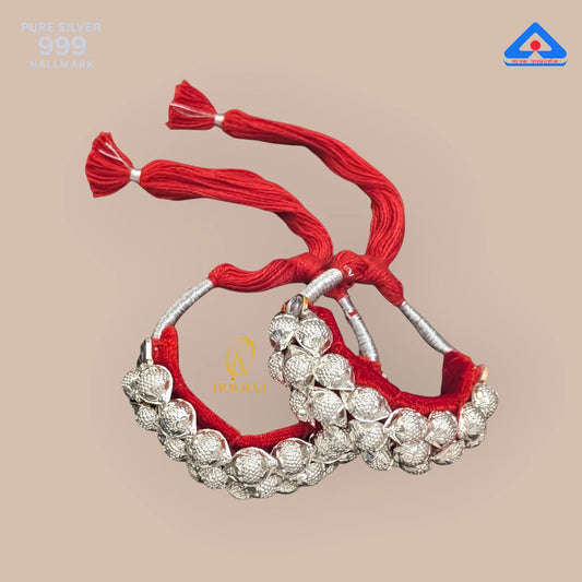 Holraj branded 999 purity silver Raj Ponchi with red thread on a beige background.