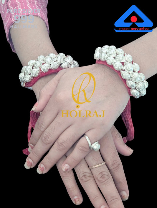 Hands wearing silver Holraj branded 999 purity silver ponchi with a visible brand logo on a black background