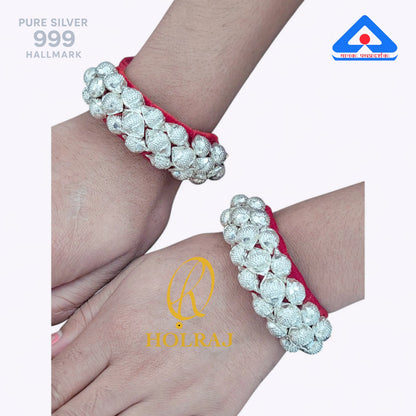 Holraj branded 999 purity Silver Raj Ponchi with red cord on a wrist.